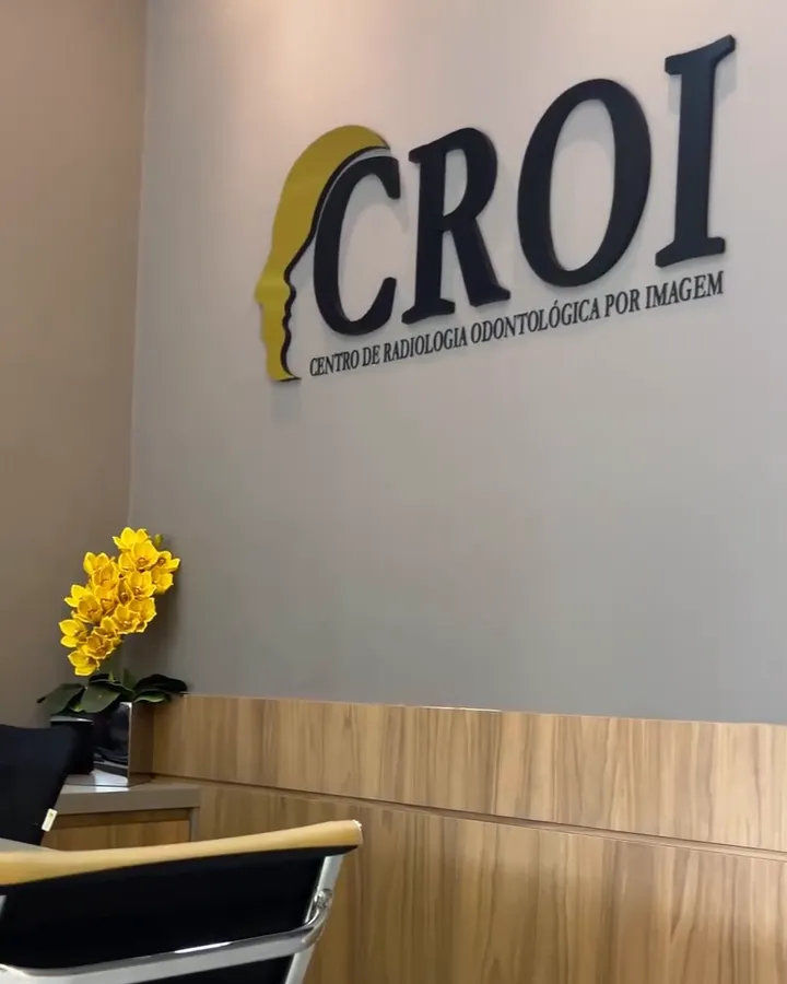 Recepção da CROI com o logo na parede, cadeira e orquídea