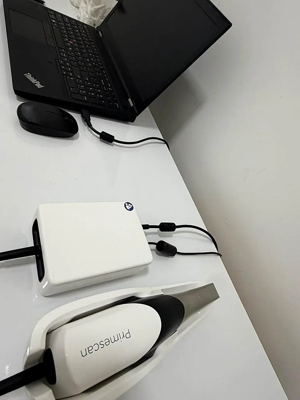 Scanner intraoral Primescan sobre a bancada, ao lado de um notebook